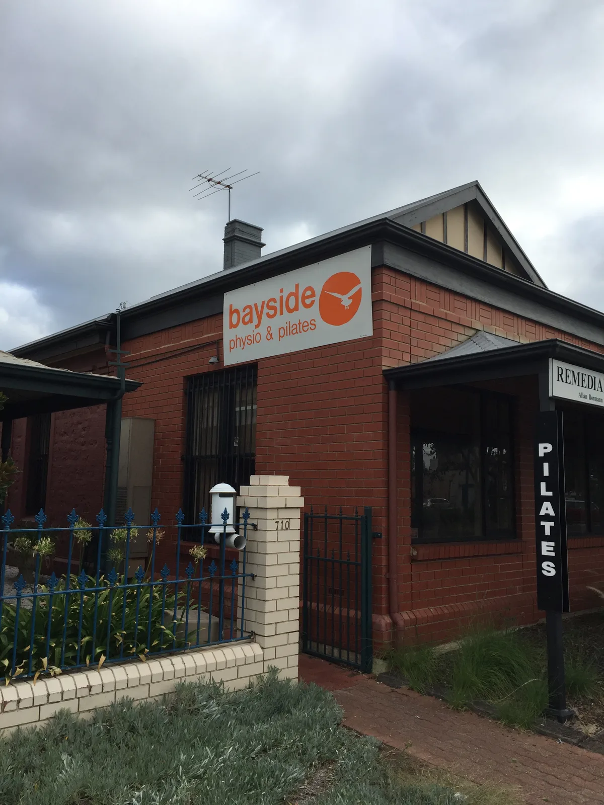 オーストラリア・グレネルグのBayside Physio & Pilatesの外観。赤レンガの建物にbayside physio & pilatesの看板とPILATESの縦看板が掲げられている